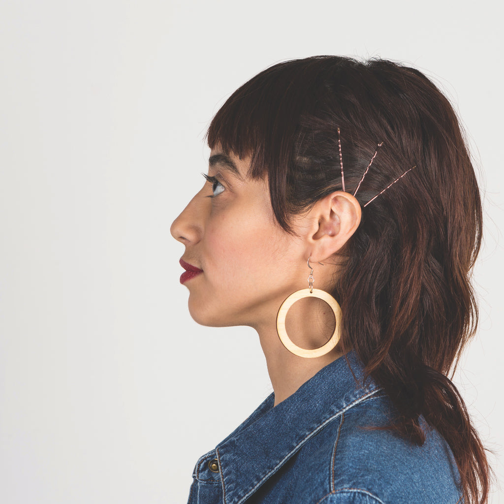 Model wearing medium laser cut wood earrings from Create Laser Arts