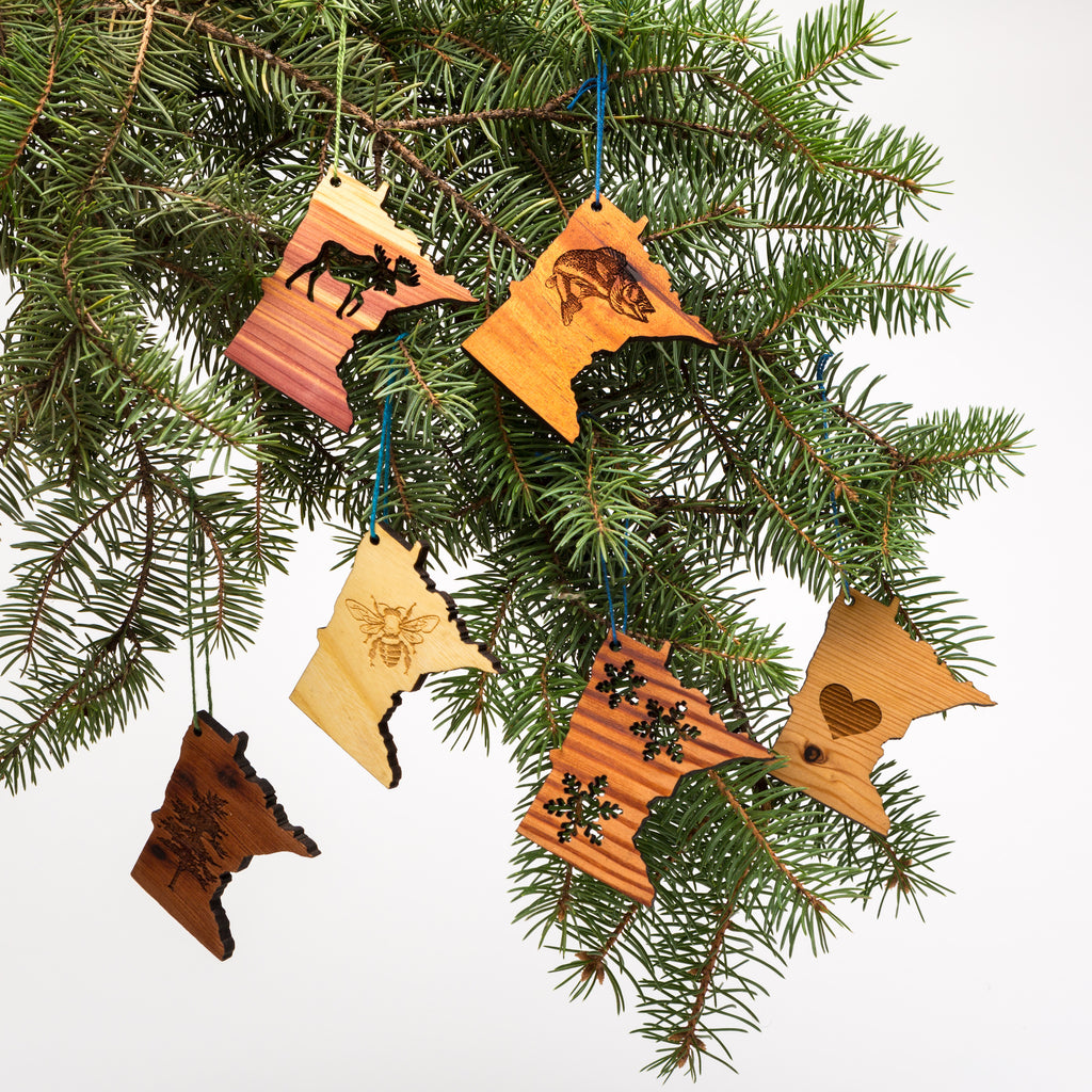 Laser cut wood minnesota-shaped ornaments hanging from a tree